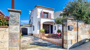 Una casa a due piani con facciata in pietra, un patio piastrellato e un piccolo giardino.