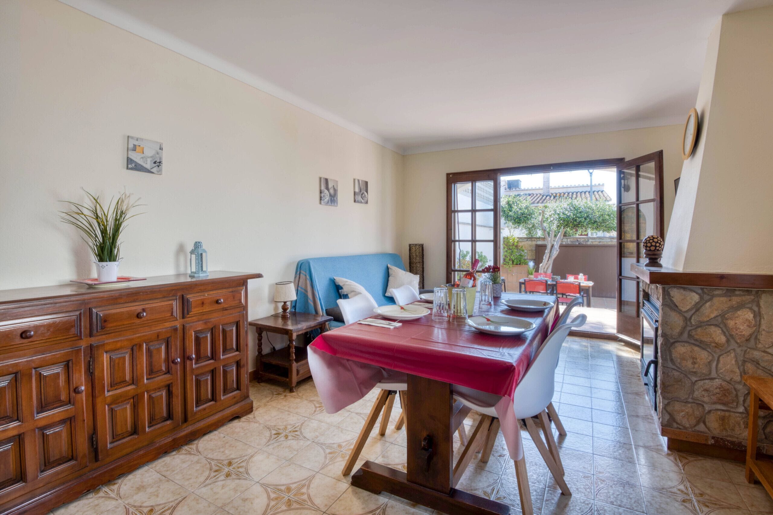Un coin repas avec une table dressée pour deux personnes, un buffet en bois et un mur en pierre.
