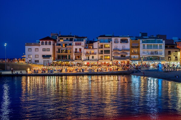 A waterfront promenade with buildings and shops along the edge, reflecting on the water.