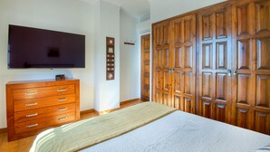 Una camera da letto con un letto, una cassettiera, un televisore e un ampio armadio in legno.