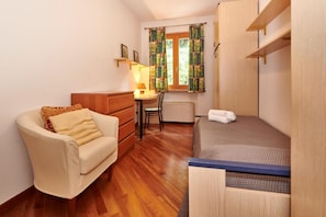 Cozy retreat with a single bed, desk, and armchair, perfect for a compact stay.