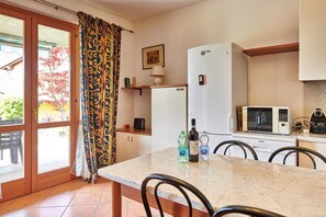 Enjoy meals at the dining table in this cozy kitchen area, equipped with a refrigerator, microwave, and oven.