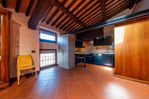Une cuisine avec un plafond en bois, une fenêtre et une chaise.
