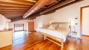 Une chambre avec un plafond en bois, un lit, une table de chevet et une vue sur l’extérieur.