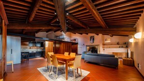 Un vaste espace de vie comprenant une table et des chaises en bois, un canapé et, au fond, une cuisine.