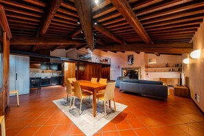 A spacious living area with a wooden dining table and chairs, a sofa, and a kitchen in the background. - ApartmentsArena - Residenza Degli Scaligeri (Verona)
