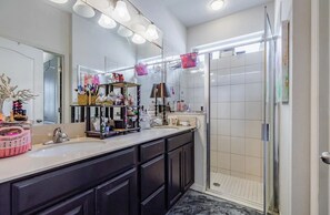 A modern bathroom with a large mirror, vanity, and a walk-in shower.