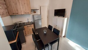 Une cuisine compacte dotée de meubles en bois, d’un réfrigérateur et d’un coin repas avec une table et des chaises.