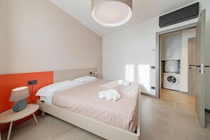 Une chambre dâhĂŽtel moderne Ă©quipĂ©e dâun lit, dâune table de chevet, dâune lampe, dâun lave-linge et dâun luminaire au plafond.