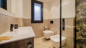 Een moderne badkamer met een witte wastafel, een toilet en een bidet.