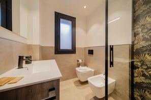Ein modernes Badezimmer mit einem weißen Waschbecken, einer Toilette und einem Bidet.