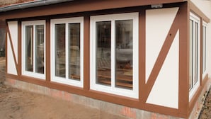 A building with a brick facade, a flat roof, and a series of windows with white frames.