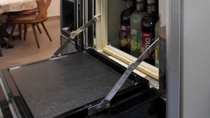 A kitchen with a built-in refrigerator, a microwave, and a shelf with bottles.