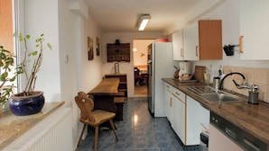 A kitchen with a wooden table, chairs, a refrigerator, and a sink.