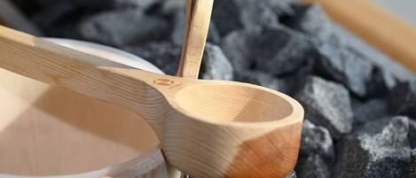 A wooden spoon resting on a bowl with a blurred background of black stones.