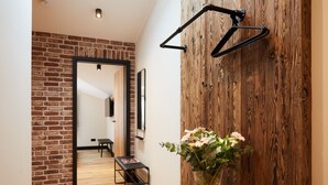 Un pasillo con pared de madera, un banco, un florero con flores y una lámpara colgante.