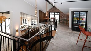Una cocina moderna con techo alto, pared de ladrillo visto y un refrigerador grande lleno de bebidas.