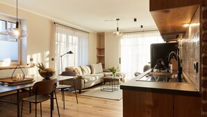 Una cocina moderna con armarios de madera, un lavamanos de acero inoxidable y un hervidor eléctrico negro.