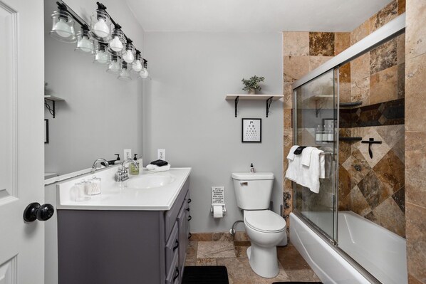 Un baño moderno con tocador, inodoro y ducha con mampara de vidrio.