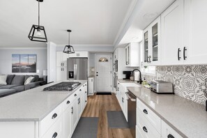 Una cocina moderna con armarios blancos, una isla central, un refrigerador y un tostador.