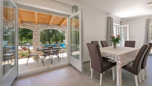 A dining area with a table and chairs, a view of an outdoor swimming pool, and a stone archway. - Villa Irena Funtana in a quiet location, with pool close to Zelena Laguna Resort (Funtana)