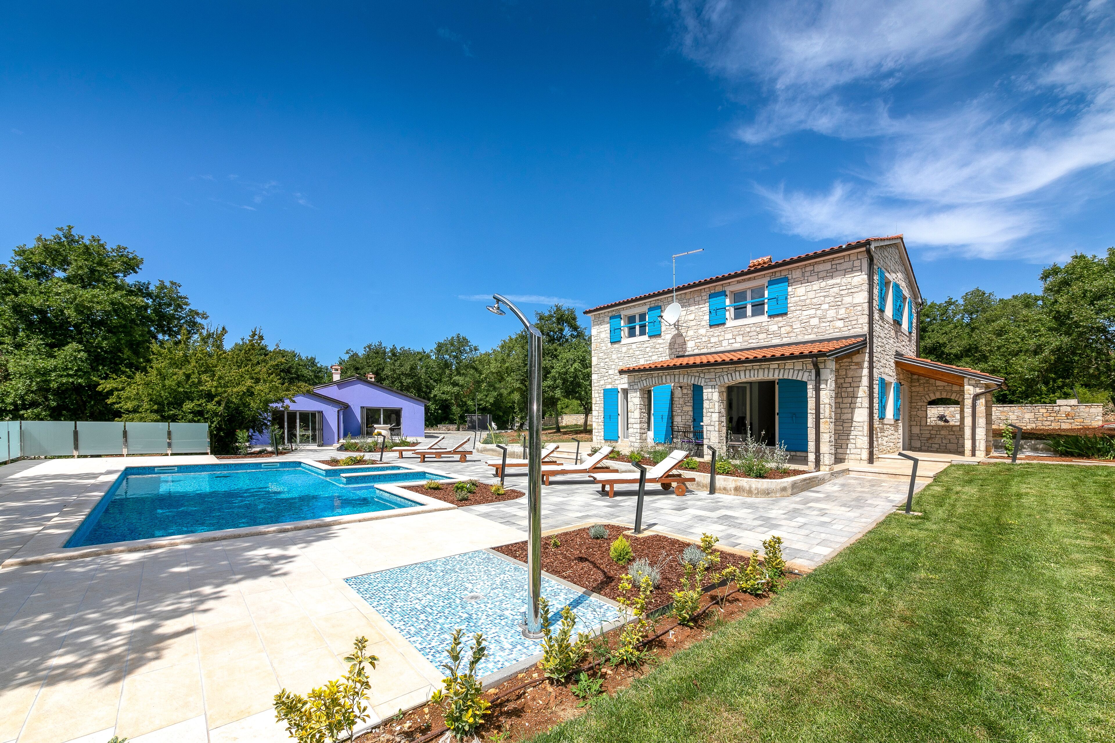 A house with a swimming pool, a patio with lounge chairs, and a garden area.