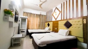 A hotel room with two beds, a ceiling fan, a TV, a small table, and a window with curtains. - White Rose Suites Ltd (Dhaka)