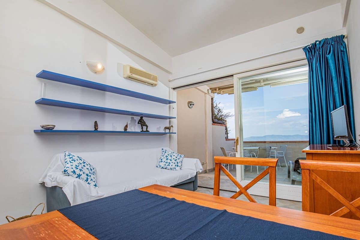 Une chambre avec un lit, un bureau et un balcon offrant une vue agréable.