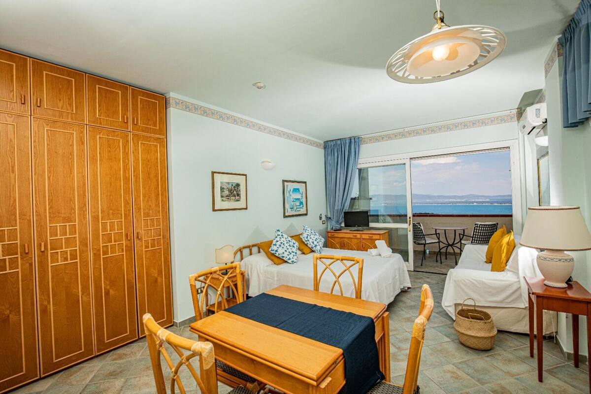 Une chambre d’hôtel avec un coin repas, un lit donnant sur une vue agréable et un balcon avec vue sur la mer.