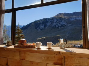A wooden table with a loaf of bread, a jar of pickles, and a coffee maker.