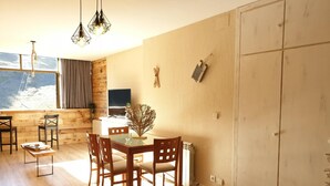 A dining area with a wooden table and chairs, a TV, and a view of the outdoors.