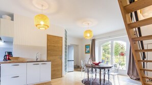A modern kitchen with white cabinets, a wooden door, and a dining area with a round table and chairs.
