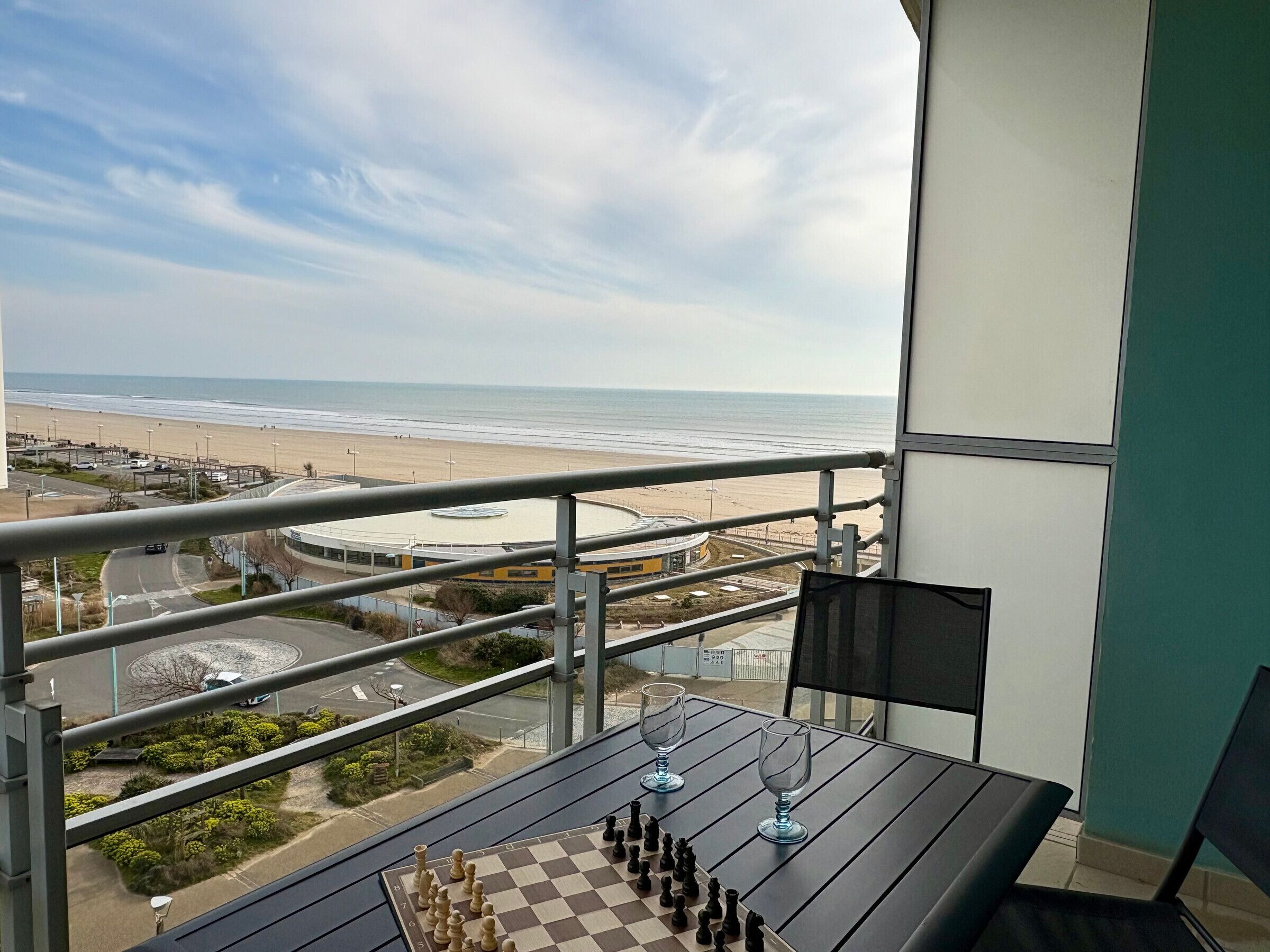 Un échiquier sur un balcon donnant sur une plage et un rond-point.