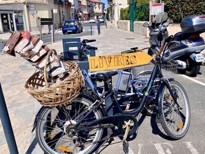 Bicycle parked on a charming street, equipped with a basket and a sign reading 'LIVRES'.