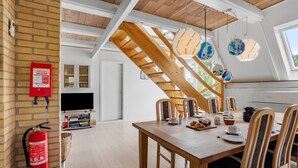 Un coin repas avec une table et des chaises en bois, un escalier et un extincteur fixé au mur.