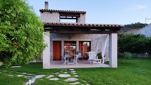 A small stone house with a patio, a dining area, and a garden.