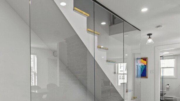A modern interior with a glass partition, a staircase, and a patterned rug. - Queen Top Suite 2BR Free Parking Modern (St. John's)