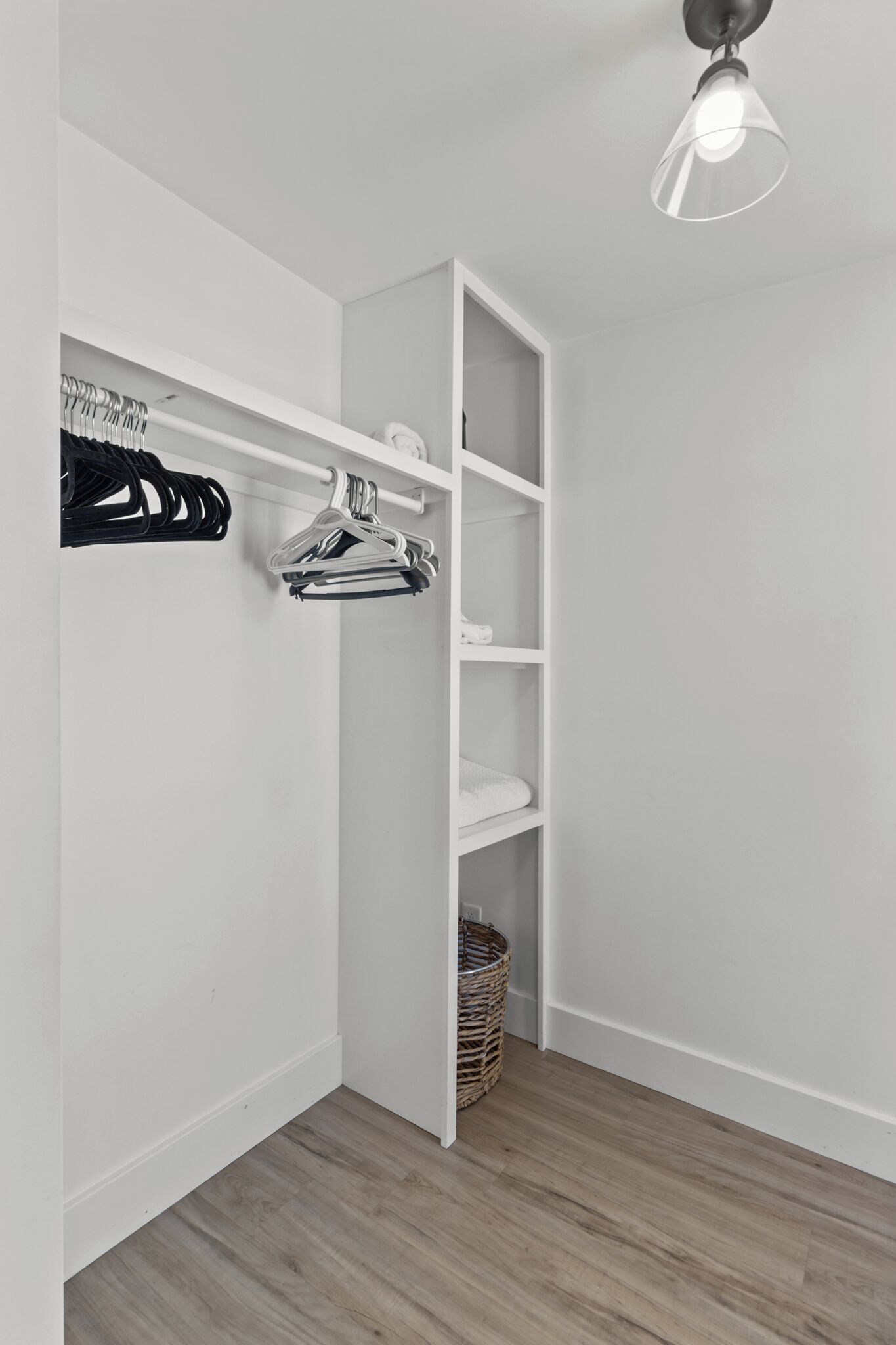 A walk-in closet with white shelving, a hanging rod, and a basket.