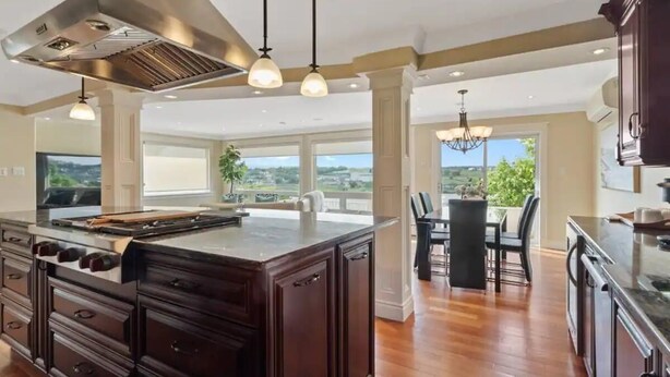 A spacious kitchen with a large island, dark wooden cabinets, and a view of the outdoors.