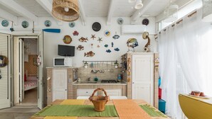 Cozinha com ilha central, micro-ondas e pia. Há pratos decorativos na parede e uma cesta na ilha.