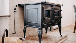 Um armário de madeira preta com pés ornamentados, apoiado em um chão de azulejos com padrão de mosaico.