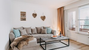 Uma sala de estar com um sofá, uma mesa de centro e uma janela com cortinas.