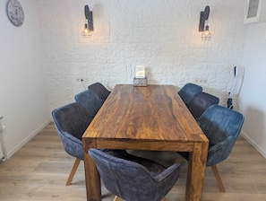Una mesa de conferencias con seis sillas, un pared de ladrillo blanco y dos lámparas fijadas a la pared.