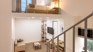 A loft-style bedroom with a bunk bed, a TV mounted on the wall, and a bookshelf. - Fervença Boutique Palace 1 by HostWise (Vila Nova de Gaia)