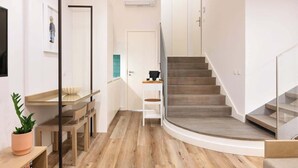 A modern interior with a curved staircase, a dining area with a glass table, and a potted plant. - Fervença Boutique Palace 1 by HostWise (Vila Nova de Gaia)