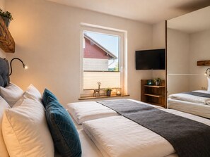 Ein Schlafzimmer mit einem Bett, Nachttischen, einem Fernseher und einem Fenster mit Jalousien.