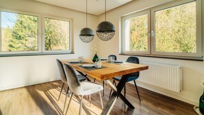 A modern dining room with a wooden table, black chairs, and pendant lights. - Holiday Apartment "Fichte" (Braunlage)
