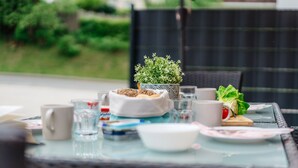 A dining table with a potted plant, bowls, plates, and cups.