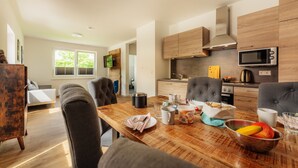 A modern kitchen with wooden cabinets, a microwave, and a dining area with a wooden table and chairs.