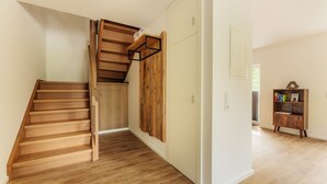 A wooden staircase leading to a landing with a wooden wall panel and a bookshelf.